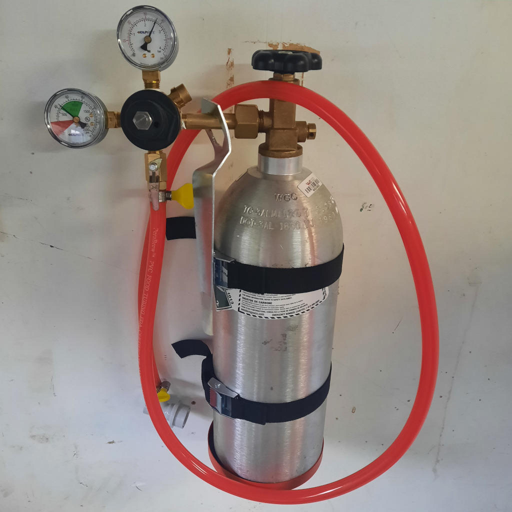 A picture of a CO2 tank mounted on a wall with a CO2 regulator and gas line attached